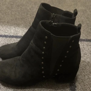 Svarta boots från Duffy - Snygga svarta boots från Duffy med dragkedja och nitar som detaljer. Perfekta för en stilren look. Tillverkade i mocka för en mjuk känsla.använd ett par gånger 