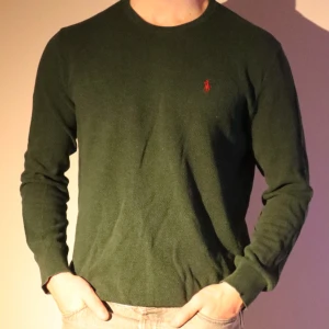 Grön långärmad tröja från Ralph Lauren - Säljer en stilren grön långärmad tröja från Ralph Lauren i mjuk pima bomull. Tröjan har en broderad röd logotyp på bröstet. Perfekt för en avslappnad och snygg look.