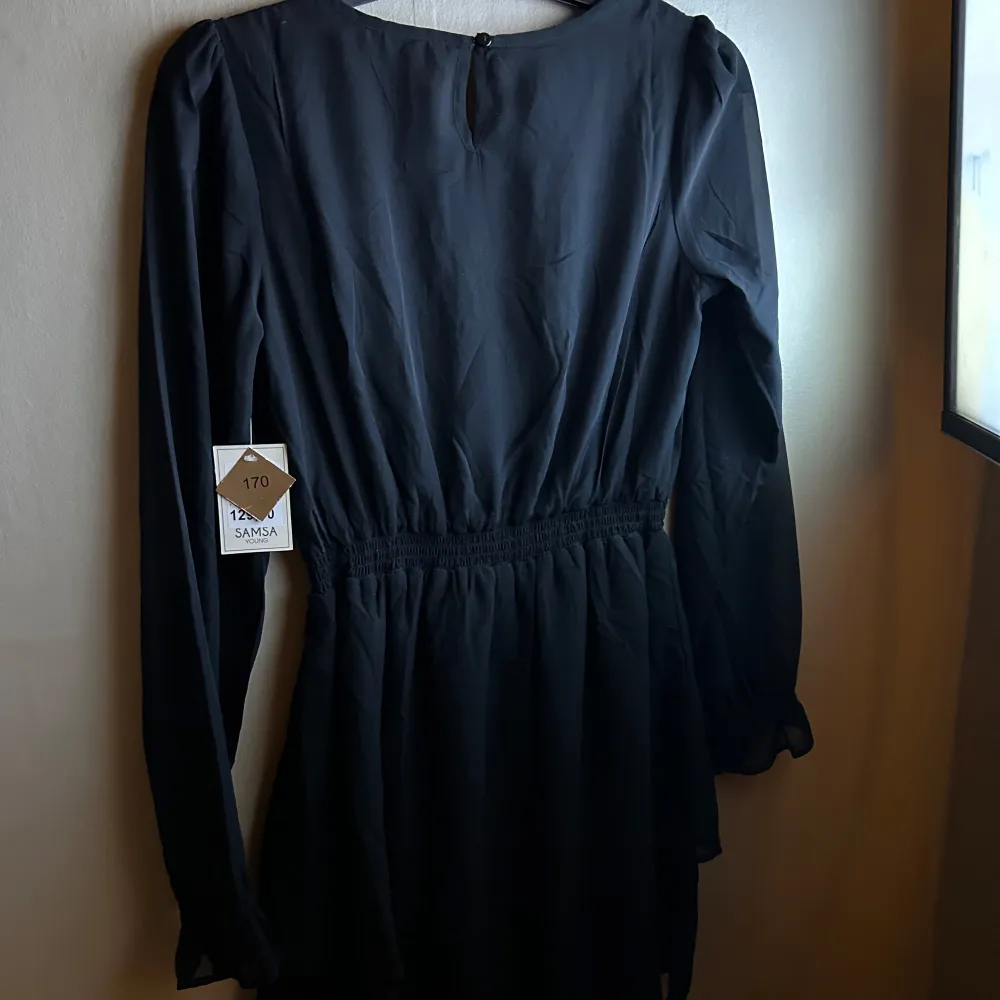 Elegant svart klänning från Ullared med v-ringning och långa ärmar. Den har en elastisk midja som ger en smickrande passform. Perfekt för en stilren look.. Mekot.