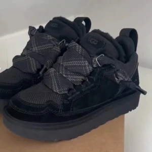  UGG lowmel - Snygga svarta sneakers från UGG med ett rutigt mönster och bred snörning. Skorna har en robust sula och är tillverkade i mocka och syntetmaterial, vilket ger en stilren och modern look. Slutsålda överallt . Även helt nya. Nypris :3000 kr