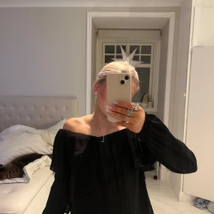 Svart offshoulder topp - Snygg svart offshoulder topp med långa ärmar. Perfekt för en stilren och elegant look. Passar bra till både jeans och kjol.