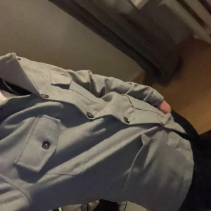 Grå kavaj från Dressmann - Snygg grå kavaj från Dressmann i slim fit. Kavajen har knappar framtill och flera praktiska fickor. Perfekt för en stilren look. Vägger  65 kilo, och är 176 cm så borde sitta  perfekt på nån i den längden! Får många pris förslag. Först till kvarn. 