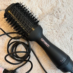 Amika Hair Blow Dryer Brush 2.0 - Säljer en Amika Hair Blow Dryer Brush 2.0. Hair Blow Dryer Brush 2.0 är en varmluftsborste med 3 justerbara värme- och hastighetslägen. Varmluftsborsten har en tourmalinbeläggning som genererar negativa joner och infraröd värme som slätar ut håret och minimerar frizz. Borsthuvudet är ca 10 cm långt och designat för att ge extra volym till rötterna. Varmluftsborsten har långa nylonborst som reder och slätar ut håret samt korta borst som ökar studsen och glansen i håret. Nypris 1099kr