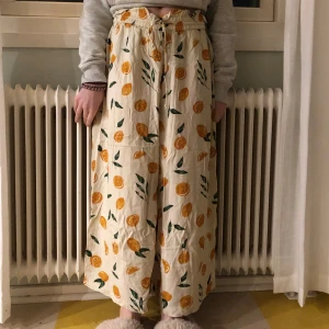 Byxor med apelsinmönster - Snygga och bekväma beige byxor med ett färgglatt apelsinmönster. Har snöre i midjan så du kan justera! (Hade dem på en skolavslutning för länge sedan och har sedan dess inte används!) 