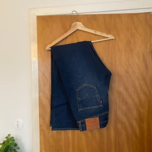Levi's 501 jeans - Säljer ett par klassiska Levi's 501 jeans i mörkblå denim. De har en rak passform och är tillverkade i bomull. Perfekta för en tidlös stil. Helt oanvända