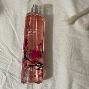 Japanese Cherry Blossom Body Splash - Fräsch och blommig body splash med doft av japansk körsbärsblomma. Flaskan är genomskinlig med rosa vätska och dekorerad med vackra körsbärsblommor. Perfekt för en uppfriskande känsla under dagen. Innehåller 236 ml. Helt ny och oanvänd 