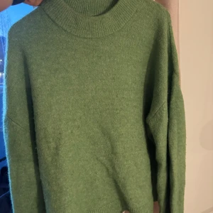 Grön stickad tröja - Mysig grön stickad tröja med ribbad krage och långa ärmar. 