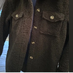 Svart teddyjacka med knappar - Mysig svart teddyjacka med knappar framtill och två bröstfickor. Perfekt för kyligare dagar med sin mjuka och varma textur. Passa på nu när det är gratis frakt(:🫶 vid snabb köp diskuteras pris gärna