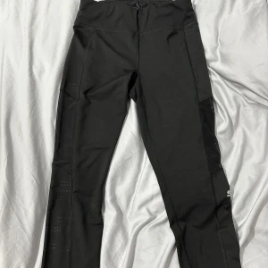 Svarta träningsleggings från Puma - Snygga svarta träningsleggings från Puma med hög midja och diskreta detaljer. Perfekta för gymmet eller löprundan. Tillverkade i ett stretchigt och bekvämt material som ger bra rörelsefrihet.