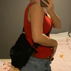 Svart axelväska med fickor - Snygg svart axelväska med justerbar rem och flera praktiska fickor på utsidan och insidan. Finns dragkedja för att stänga väskan