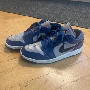 Nike Air Jordans i blått och grått - Snygga Nike Air Jordans i en stilren kombination av blått och grått. Skorna har en klassisk design med snörning och perforerade detaljer på tån för extra ventilation. Perfekta för både vardag och sportiga aktiviteter.