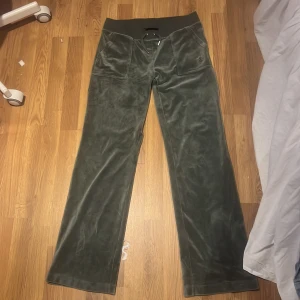 Gröna mjukisbyxor från Juicy Couture - Snygga gröna mjukisbyxor från Juicy Couture med bred resår i midjan och snörning. Byxorna har fickor både fram och bak, vilket ger en avslappnad look. Perfekta för en chill dag hemma eller en avslappnad utflykt.