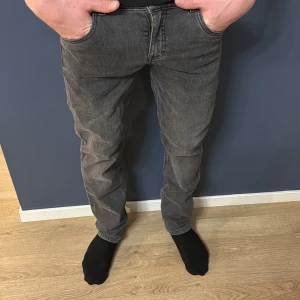 Grå jeansbyxor - Snygga grå jeansbyxor med en klassisk femficksdesign. Byxorna har en rak passform och är perfekta för en avslappnad stil. De är tillverkade i ett slitstarkt material och har en bekväm midwaist. Säljs till billigt pris!