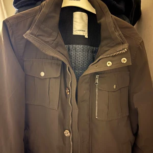 J.Lindeberg Bailey Field - Snygg brun jacka från J.Lindeberg med dragkedja och knappar. Den har flera praktiska fickor och en stilren design. Perfekt för höst och vår. Kom pm för frågor