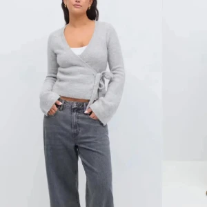 Grå omlottkofta från Gina Tricot - Snygg och stilren grå omlottkofta från Gina Tricot. Koftan har en knytning i sidan och är tillverkad i ett mjukt material. Perfekt för lager-på-lager och passar till många olika outfits. Köpte den precis och den är helt ny men passade ej mig 🌸