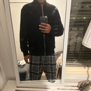 Svart teddyjacka med dragkedja - Mysig svart teddyjacka med dragkedja framtill. Jackan har långa ärmar och ribbade muddar vid ärmslut och nederkant. Perfekt för kyliga dagar.