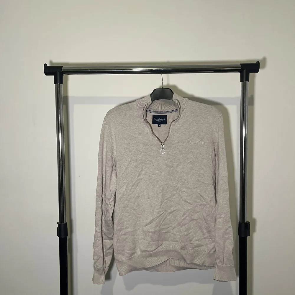 Säljer en stilren beige tröja från Bouléid med dragkedja vid halsen. Tröjan har långa ärmar och är perfekt för en klassisk look. Passar bra till både jeans och chinos.. Neuletakit & Villapaidat.