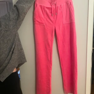 Rosa mjukisbyxor från Juicy Couture - Snygga rosa mjukisbyxor från Juicy Couture med snörning i midjan och praktiska fickor både fram och bak. Perfekta för en avslappnad stil. Inga defekter och de är i storlek M. Använda några gånger och byxorna köptes för 1200kr. Köp sker via ”köp direkt” knappen!🩷