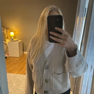 Beige kofta med knappar - Lånade bilder!! Säljer en mysig beige kofta med stora knappar framtill. Koftan har långa ärmar och två fickor, perfekt för kyliga dagar. Passar bra till både jeans och kjol.