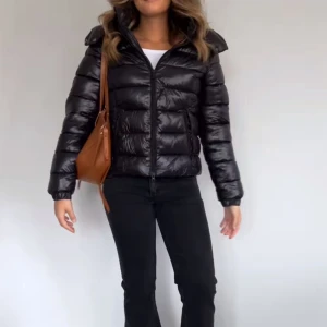 Svart pufferjacka  - Snygg och trendig svart pufferjacka 'Nikki' med dragkedja och hög krage. Perfekt nu till vintern med vaddering som håller dig varm. Jackan är helt ny och endast testad i butik.