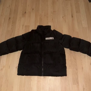 Svart pufferjacka från Hoodrich - Snygg svart pufferjacka från Hoodrich med dragkedja och logga på bröstet. Storlek S, Köpte för 1200 men säljer för 500