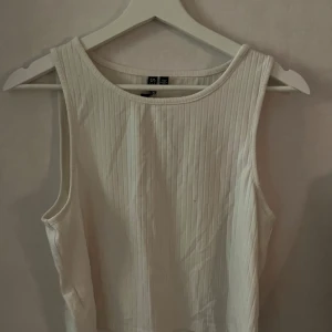 Vit ribbad linnetopp från Pieces - Säljer en stilren vit ribbad linnetopp från Pieces. Toppen är ärmlös och har en rund halsringning, perfekt för varma dagar eller som lager under en jacka.