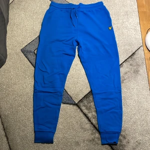 Blå mjukisbyxor från Lyle & Scott - Säljer ett par snygga blå mjukisbyxor från Lyle & Scott. De har en bekväm passform med snörning i midjan. Knappt använda då de ej passar min stil. Storlek L passar även M