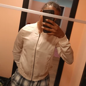 Jacka - Den är en lätt höst eller vår jacka. Den är inte så tjock/varm men den är silkig och skön. Inte använd så många gånger. Fin tan färg.