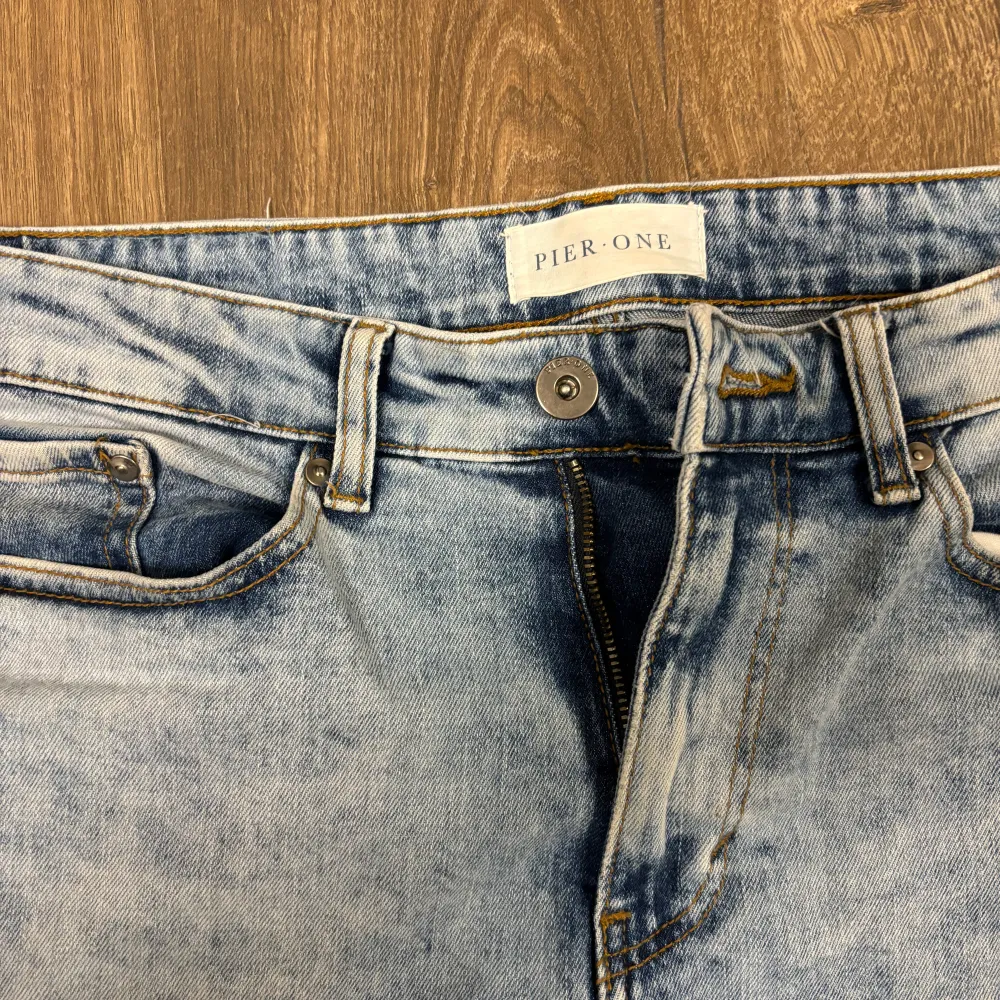 Säljer ett par ljusblå jeans från Pier One. De har en klassisk femficksdesign och en knappgylf. Jeansen har en snygg tvättad look som ger dem en avslappnad stil. Perfekta för vardagsbruk!. Jeans & Byxor.