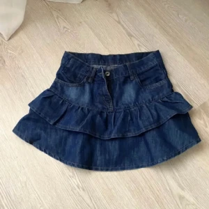Jeans volang kjol - Säljer denna jeanskjolen med volanger. Köpt på plick men aldrig använd eftersom den inte passar. Midjemåttet rakt över är 33 cm. Köparen står för frakten❤️