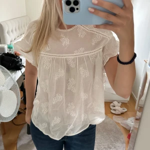 Vit blus från Zara Trafaluc - Säljer en söt vit blus från Zara Trafaluc. Den har ett fint broderat mönster och korta ärmar. Perfekt för sommardagar eller en avslappnad vårlook. Blusen är i nyskick och har en lös passform.