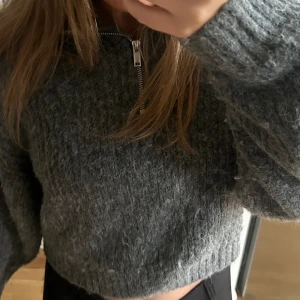 Grå stickad croppad tröja med dragkedja - Säljer en supermysig grå stickad tröja med dragkedja framtill. Perfekt för höst och vinter när du vill vara både varm och stilren. Tröjan har långa ärmar och en loose passform som gör den extra bekväm🤎