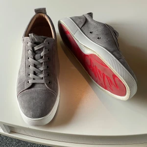  Christian Louboutin skor - Snygga grå sneakers från Christian Louboutin med den ikoniska röda sulan 🪩 Skorna har snörning och är tillverkade i ett stilrent material som ger en lyxig känsla🪩 Perfekta för dig som vill ha en touch av elegans i vardagen🪩
