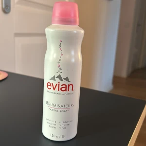 Evian Brumisateur Facial Spray - aldrig använd eller öppnad. Fräsch ansiktsspray från Evian i en vit flaska med rosa detaljer. Perfekt för att återfukta och fräscha upp huden. Innehåller 150 ml naturligt mineralvatten.