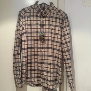 Rutig flanellskjorta från Morris - Hej säljer en stilren rutig flanellskjorta från Morris i färgen beige och bruna. Skjortan är i storlek M och i slim fit. Säljes då jag fick den i födelsedagspresent och den var för stor för mig. Den är i nyskick.