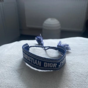 Blått armband från Christian Dior - Justerbart Christian dior armband som inte kommit till andvända. Är i nytt skick och priset är såklart inte inristat i sten