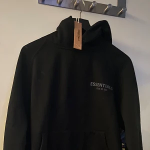 Svart hoodie från Fear of God Essentials - Säljer en svart hoodie från Fear of God Essentials med logga på bröstet. Perfekt till vintern, Det är en storlek S men sitter som en M, 