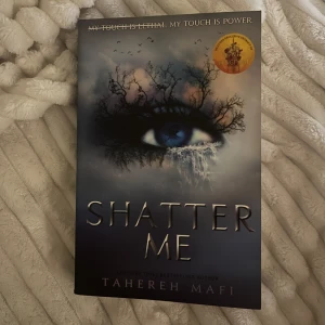 Shatter Me (Engelska)  - Boken 'Shatter Me' av Tahereh Mafi handlar om en tonårsflicka med en dödlig beröring som hålls fången. Hon måste kämpa mot de som vill använda henne som ett vapen. Omslaget visar ett öga omgivet av träd och fåglar, vilket ger en mystisk känsla. Boken är på engelska. Fick i julklapp, säljer den eftersom att jag läst färdigt! 🩷ORIGINAL PRIS: 189kr. Bok 1 av shatter me serien. 