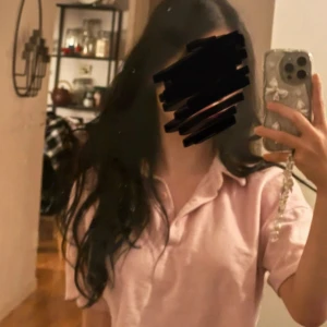 Rosa croppad polotopp från Bershka - Säljer en söt rosa croppad polotopp från Bershka med texten 'Dream Awake' broderad på bröstet. Toppen har korta ärmar och knappar framtill. Perfekt för en avslappnad stil.