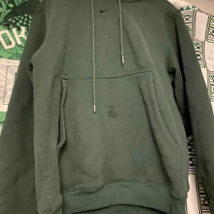 Grön hoodie från Nike - Säljer en grön hoodie från Nike med en klassisk känguruficka och justerbar dragsko i huvan. Perfekt för en avslappnad stil.