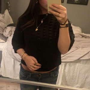 Svart croppad tröja - Snygg svart croppad tröja med trekvartsärm och ett diskret rutmönster. Perfekt för en stilren look.