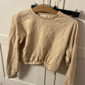 Beige croppad tröja från 157 - Säljer en beige croppad tröja från 157. Tröjan har långa ärmar och en rund halsringning. Perfekt för en avslappnad stil. Passar bra till jeans eller kjol.