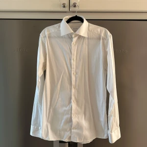 Vit skjorta från Eton - Säljer en stilren vit skjorta från Eton i storlek 38. Skjortan har en slim passform med knappar framtill. Perfekt för en elegant look, går även att ha manschettknappar på ärmarna. Ny pris 1700, blivit för liten för mig så säljer för endast 700kr. Hör av er vid några eventuella frågor!