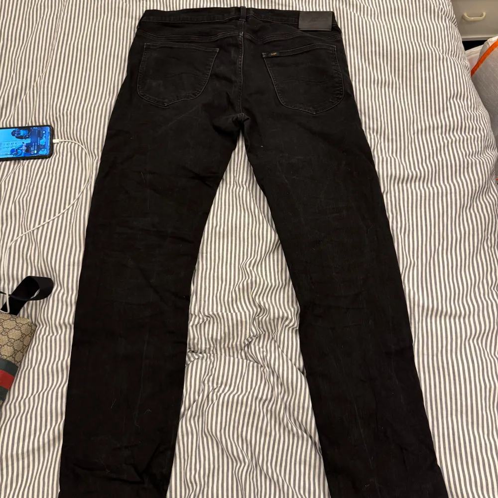 Snygga svarta jeans från Lee med klassisk design och dragkedja. Perfekta för en stilren look. De har en normal passform och är tillverkade i slitstarkt material.. Farkut & Housut.