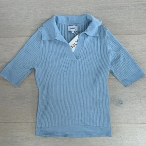Ljusblå ribbad pikétröja från ONLY - Säljer en stilren ljusblå pikétröja från ONLY. Tröjan är ribbad med en klassisk krage och korta ärmar, perfekt för en avslappnad look. Den har en mjuk och bekväm passform.