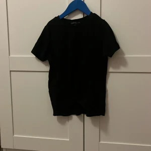Svart ribbad t-shirt från XOXO Friends - Säljer en svart ribbad t-shirt från XOXO Friends i storlek 146/152. T-shirten har korta ärmar och en stilren design som passar perfekt till vardags.