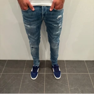 Dondup Blå slitna jeans  - Snygga blå jeans med slitningar och en slim passform. Perfekta för en avslappnad stil. De har en klassisk femficksdesign och dragkedja.  Passar 33, 32, och möjligt 31