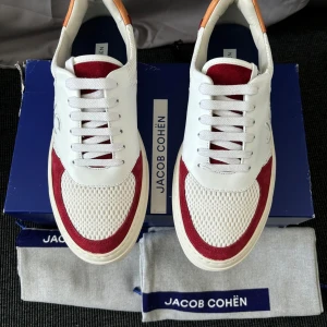 Vita och röda sneakers från Jacob Cohën - Snygga vita sneakers med röda detaljer från Jacob Cohën. Helt nya allt og medföljer vilket är box och dustbag storlek 42 pris 2999