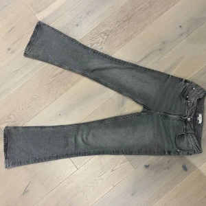 Grå jeans från Gina Tricot - Snygga grå jeans från Gina Tricot med bootcut-stil. De har en klassisk femficksdesign och en knappgylf. Perfekta för en avslappnad look.