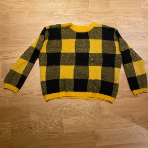 Gul och svart rutig tröja från H&M - Säljer en cool gul och svart rutig tröja från H&M. Tröjan har en klassisk rund hals och långa ärmar. Perfekt för att liva upp garderoben med lite färg och mönster!